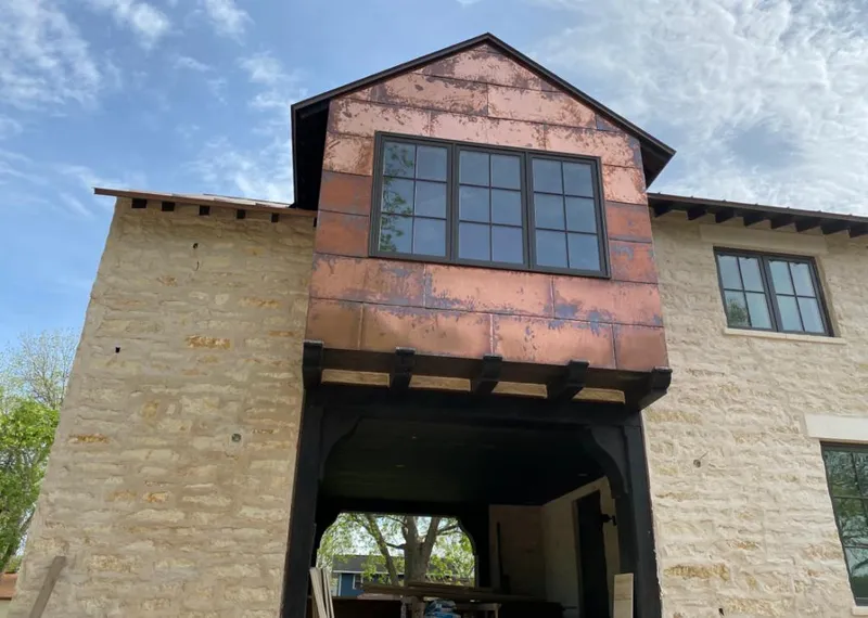 Copper metal panel facade on a stone building for Roof Repair in Dexter